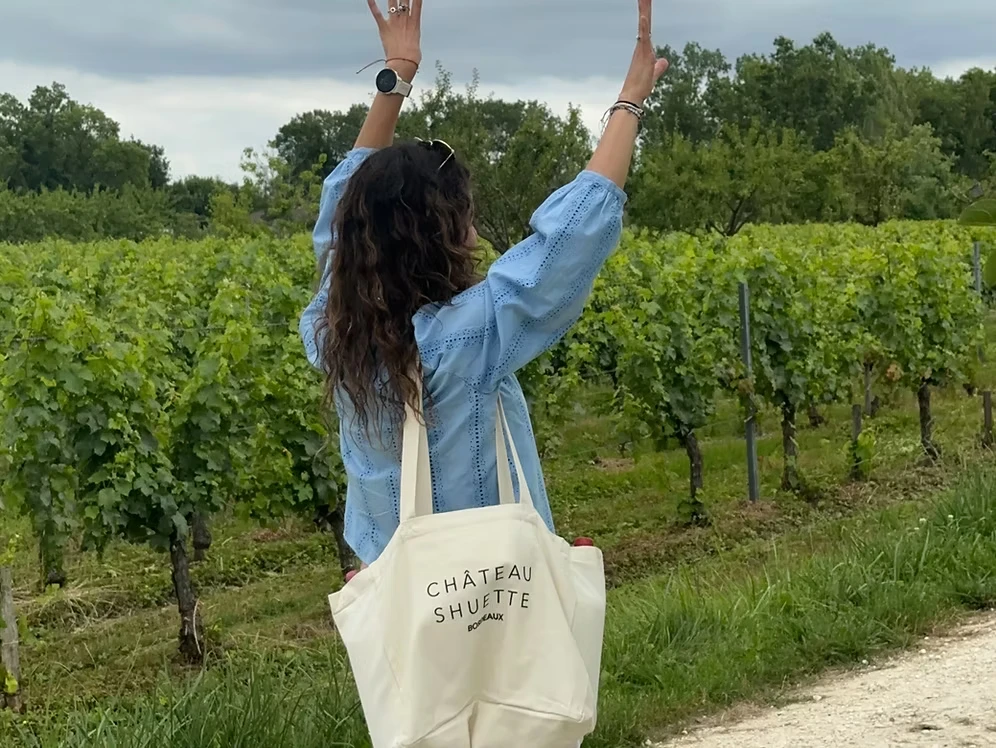 White Château Shuette tote bag carried beside the vineyard