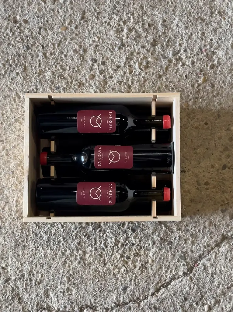 Open wooden wine box holding three Sanguis bottles